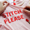 Hands stitching a slogan onto a t-shirt