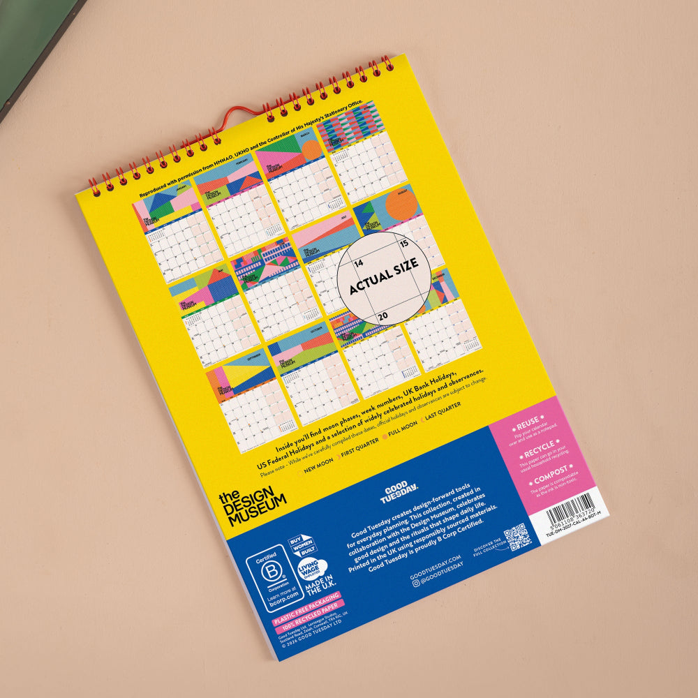 The Design Museum 2024 desk calendar shown from the back, featuring a bright yellow cover with a colorful grid preview of the monthly pages, a blue and pink bottom section with product details, and a spiral binding at the top, photographed on a beige background.