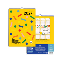 A 2027 wall calendar from The Design Museum, featuring a bright yellow cover decorated with colorful confetti-like shapes and a blue spiral binding. The back cover is partially visible behind it, showing monthly grids and a blue footer with product details.