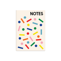 A cream-colored notebook or notepad with the word 'NOTES' printed in bold black at the top, decorated with scattered colorful geometric shapes including circles, rectangles, and lines in blue, red, green, yellow, pink, and orange.