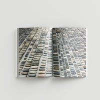 Inside page of Ai Weiwei catalogue with a photograph of various stones in rows against a gray background.