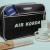 Black 'AIR KORDA' travel bag with a cup and saucer on a light background