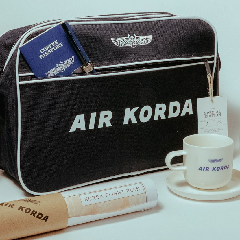Black 'AIR KORDA' travel bag with a cup and saucer on a light background