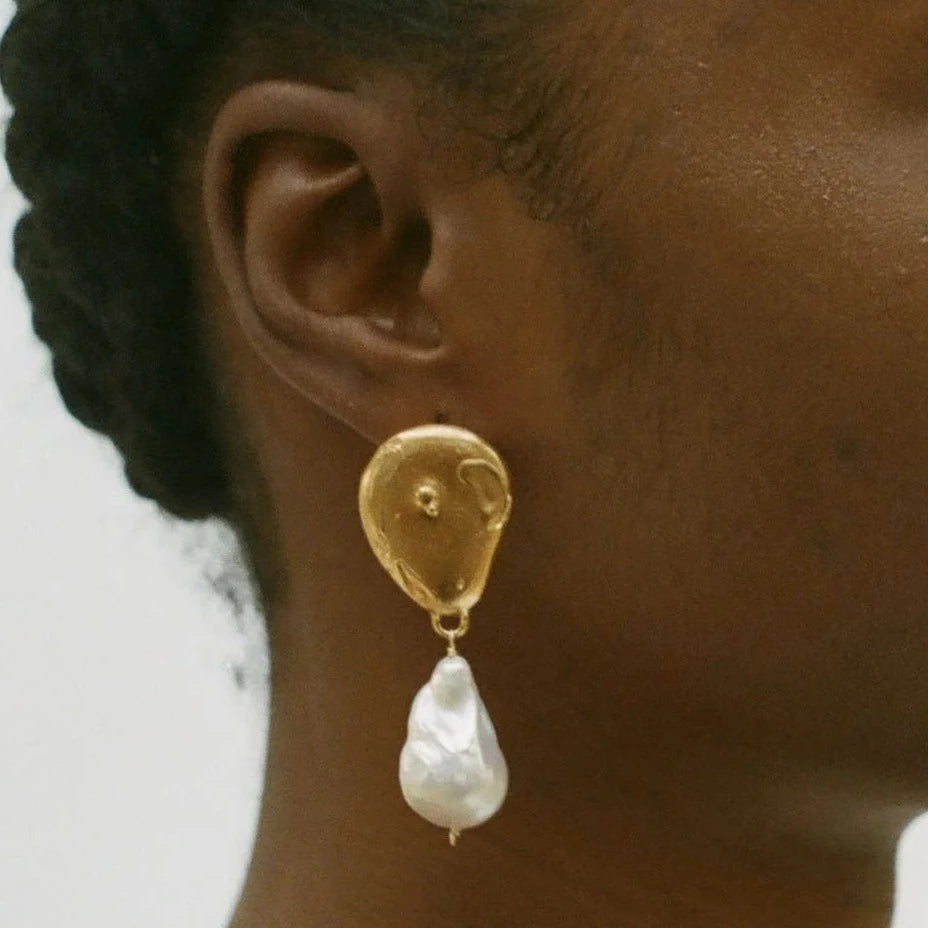 closeup of gold earring on model