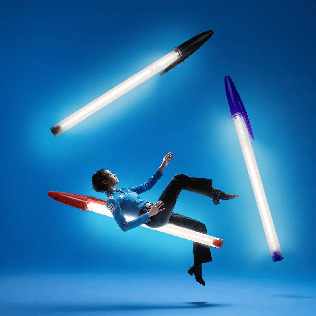 Person floating between three BIC pen lamps against a blue background