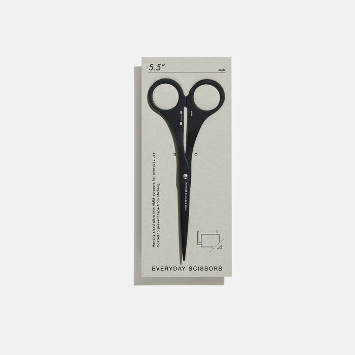 A pair of black thin scissors with grey minimalistic packaging.
