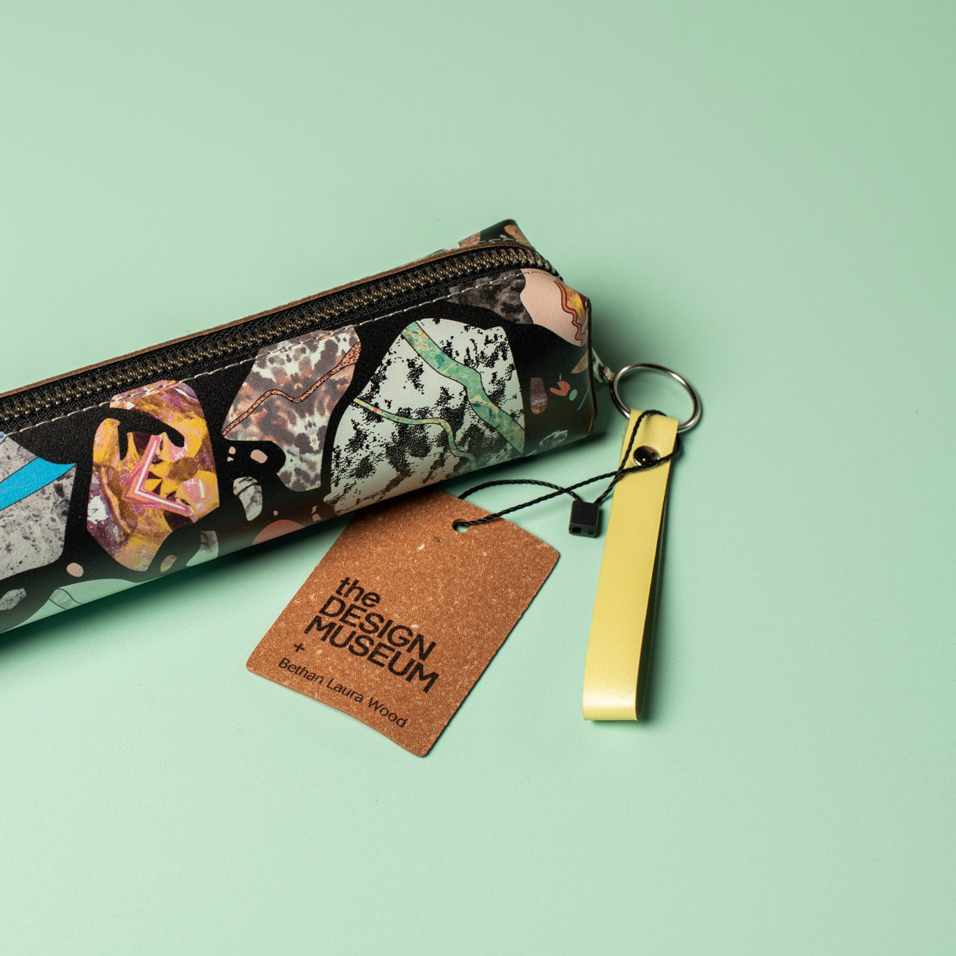 Pencil case with abstract marbled design and a tag from The Design Museum on a light green background