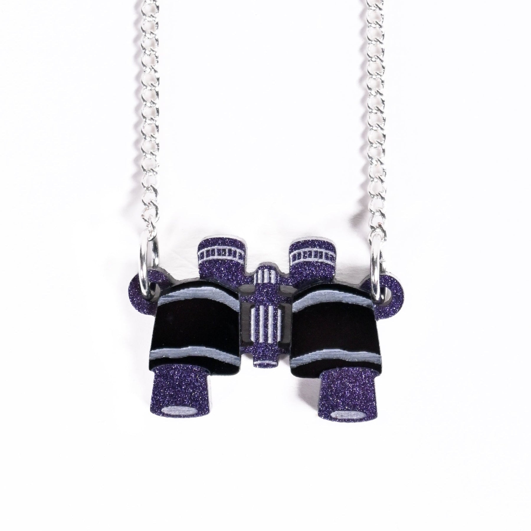 Necklace with purple and black glittery binoculars on a white background