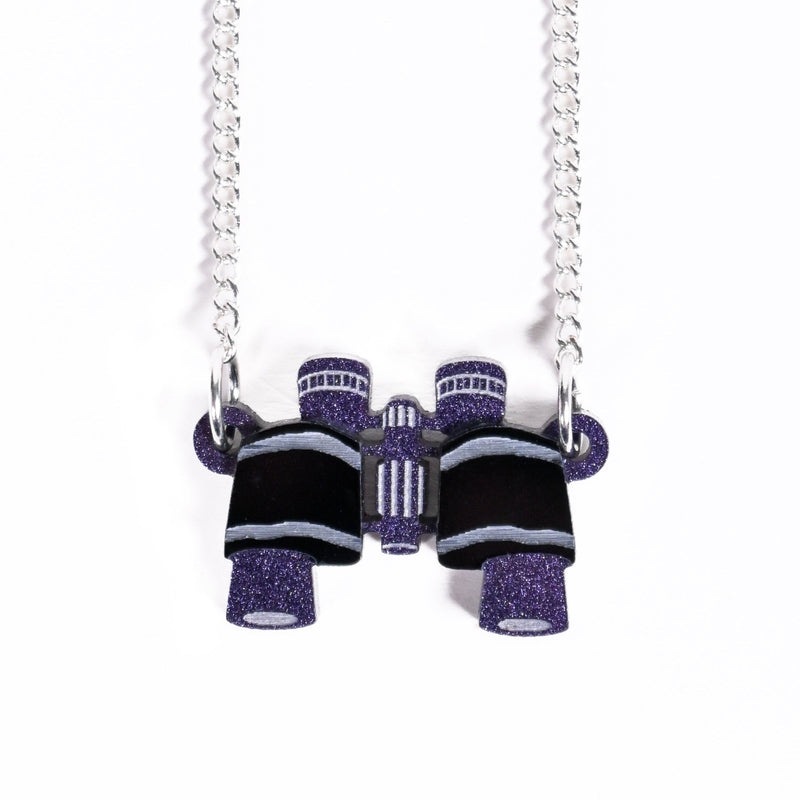 Necklace with purple and black glittery binoculars on a white background