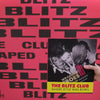 Book titled 'The Blitz Club' held against a red background with 'Blitz' text.