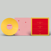 A yellow vinyl record with a pink center label reading 'ROCKET' sits beside a pink booklet and a red-and-yellow printed insert on a light gray background.