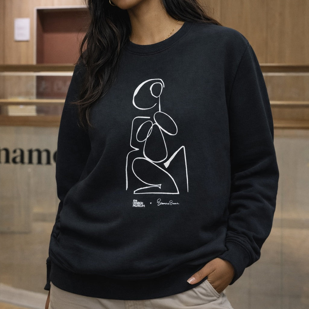 Person wearing a black sweatshirt with a white abstract design in an indoor setting