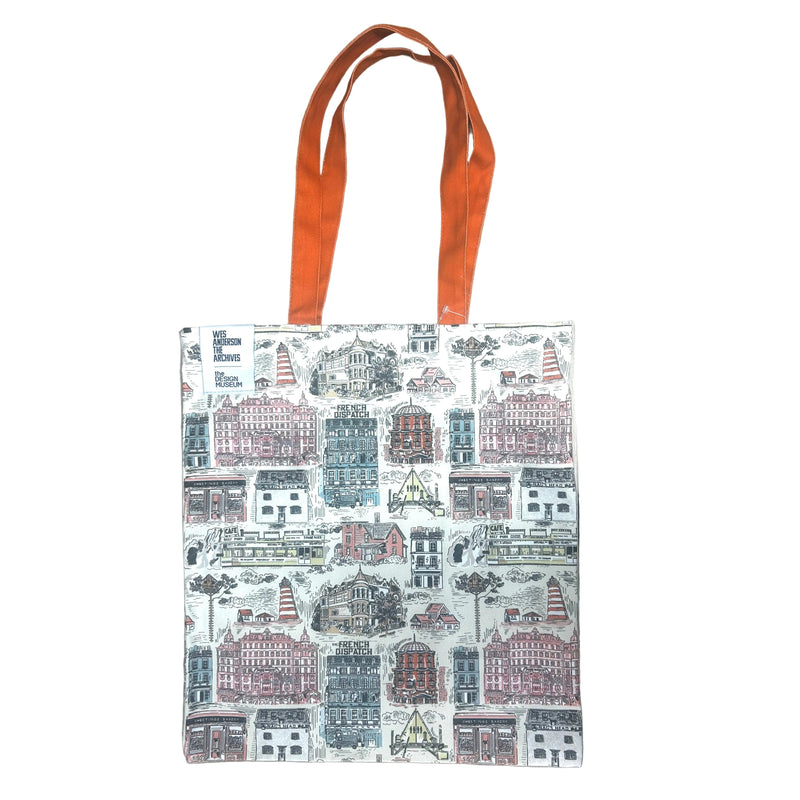 Tote bag with cityscape design and orange handles on a wooden surface