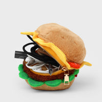 Plush burger-shaped pouch with zipper and cables inside on a light gray background