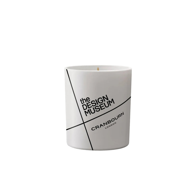 A white cylindrical candle jar with a minimalist black geometric design and text reading 'the DESIGN MUSEUM' and 'CRANBOURN LONDON', centered on a light gray background.