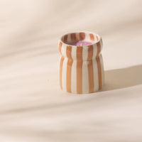 Striped ceramic cup on a beige background