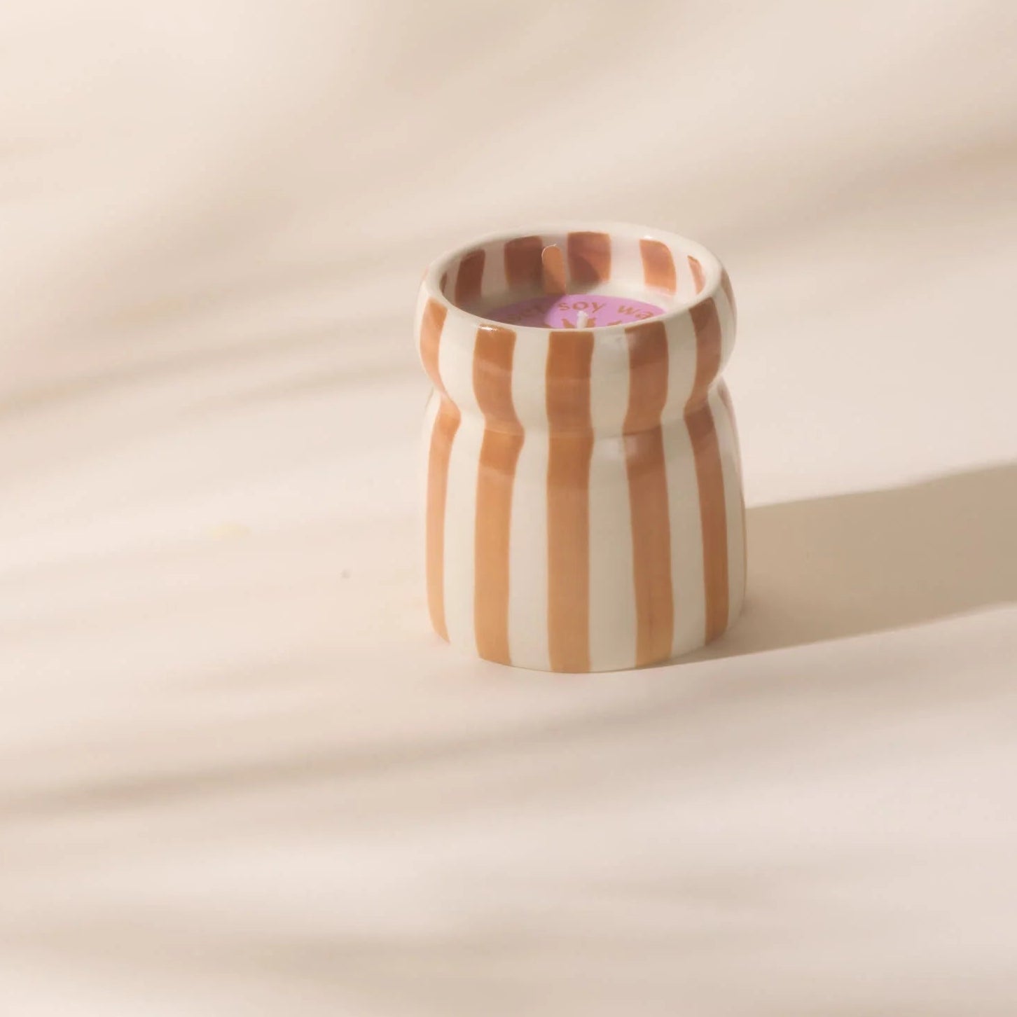 Striped ceramic cup on a beige background