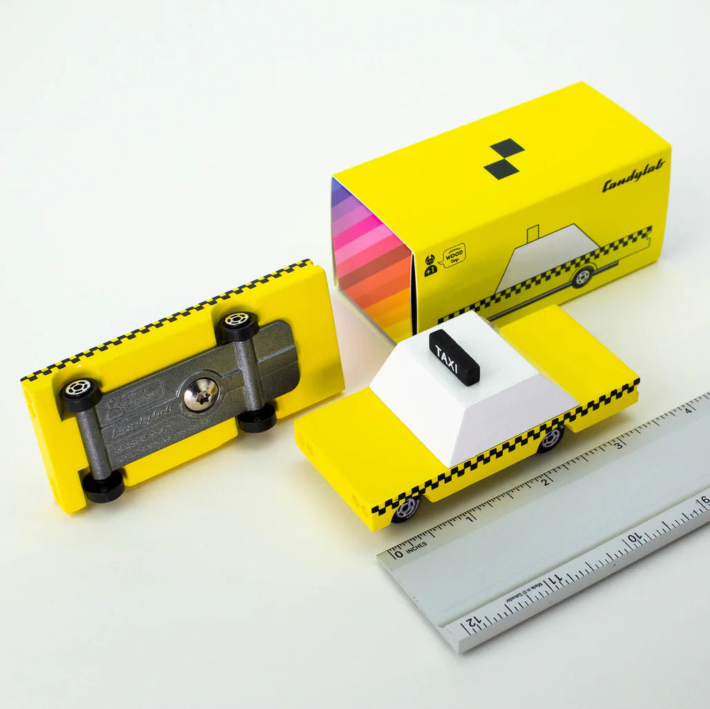 Yellow toy car with a ruler for scale on a white background 