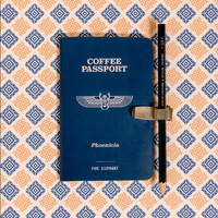 Blue 'Coffee Passport' book with a pen on a patterned background
