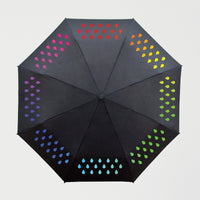 An open colour changing umbrella with a colourful raindrop pattern on a black background.