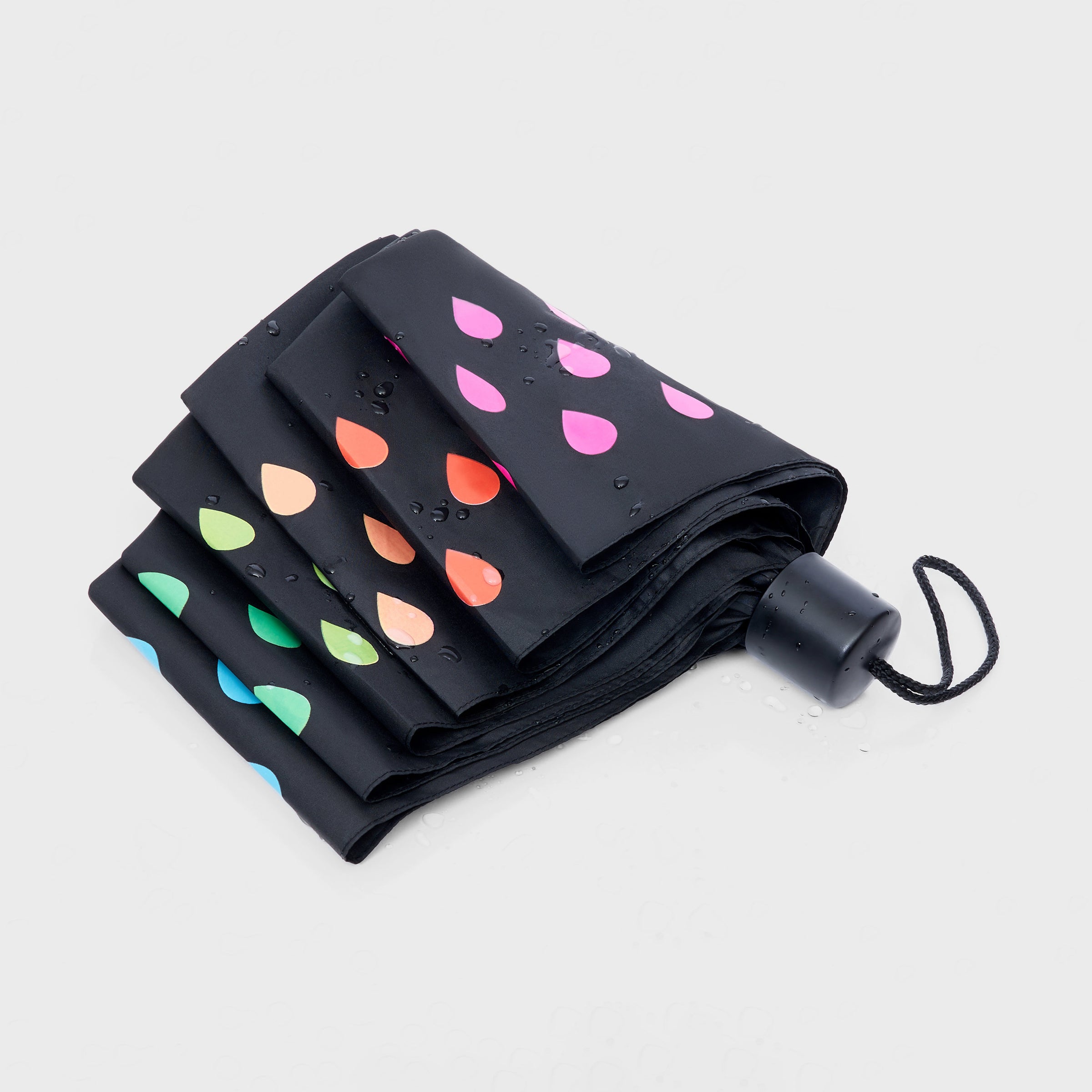 A closed colour changing umbrella with a colourful raindrop pattern on a black background.