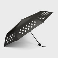 An open colour changing umbrella with a white raindrop pattern on a black background.