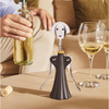 Person holding a bottle of wine with a unique corkscrew device on a table with wine glasses.