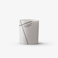 A white cylindrical scented candle with a single wick, featuring a minimalist black geometric line design and the text 'ARCHITECTURE & SCENT' printed on the front, set against a clean white background.