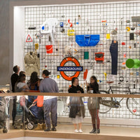 People interacting with the Design Museum Crowdsourcedwall display featuring various items and a prominent 'Underground' sign.