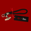 Black keychain with red string on a red background, featuring 'the Design Museum' logo.