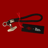 Black keychain with red string on a red background, featuring 'the Design Museum' logo.