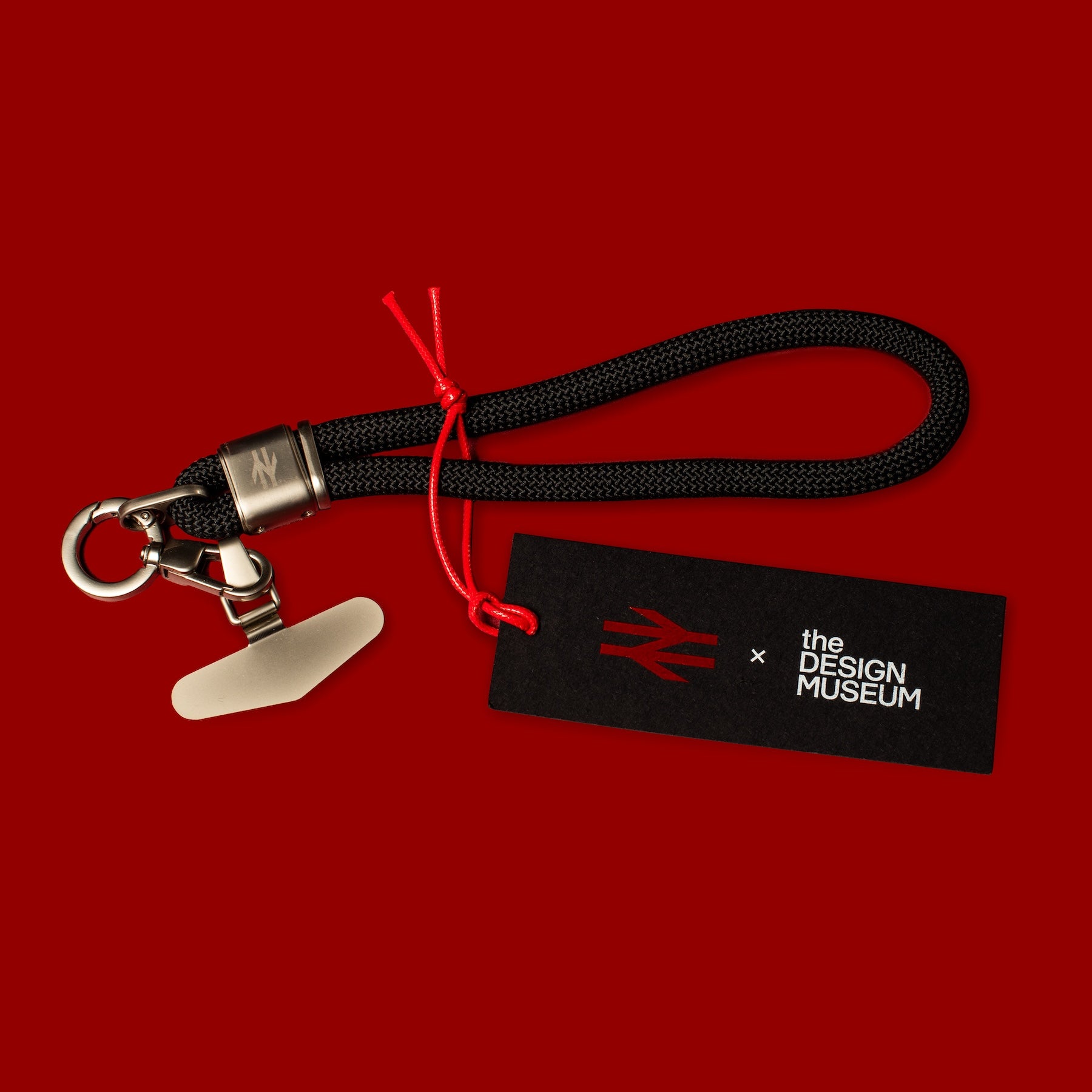 Black keychain with red string on a red background, featuring 'the Design Museum' logo.
