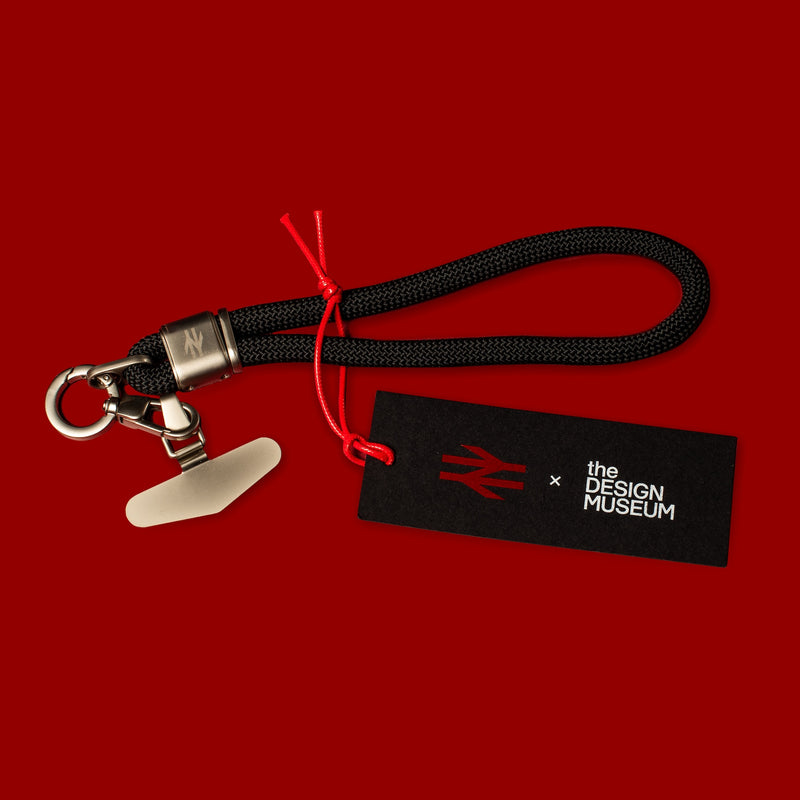 Black keychain with red string on a red background, featuring 'the Design Museum' logo.