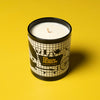 Candle in a black container with design museum branding on a yellow background