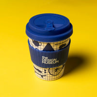 Reusable coffee cup with blue lid and design museum branding on a yellow background