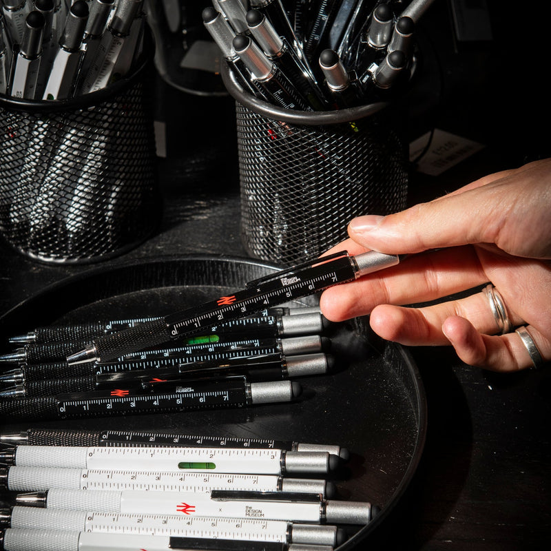 Person selecting a pen from a collection of pens on a dark surface