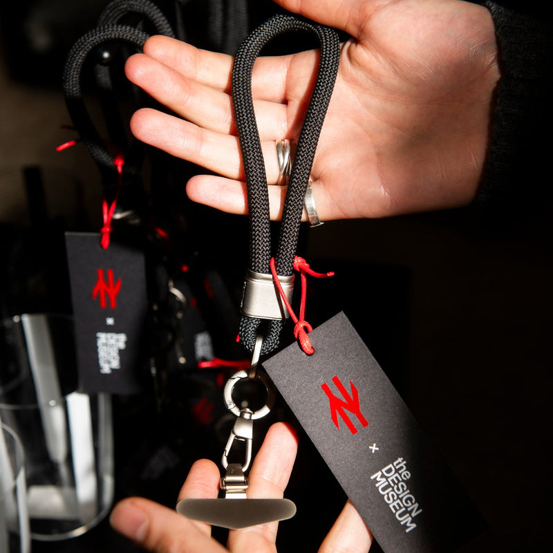 Person holding a keychain with a brand tag against a dark background