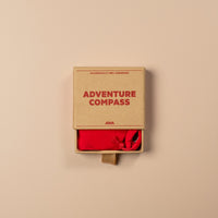 Cardboard box with 'Adventure Compass' on a beige background