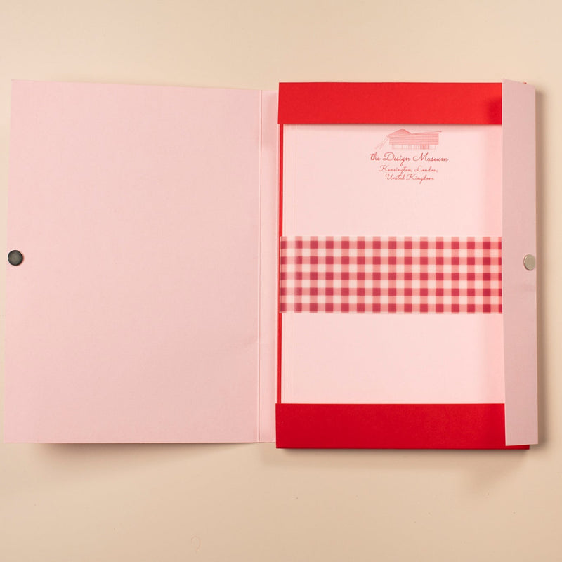 Pink notebook with a red gingham pattern on a beige background