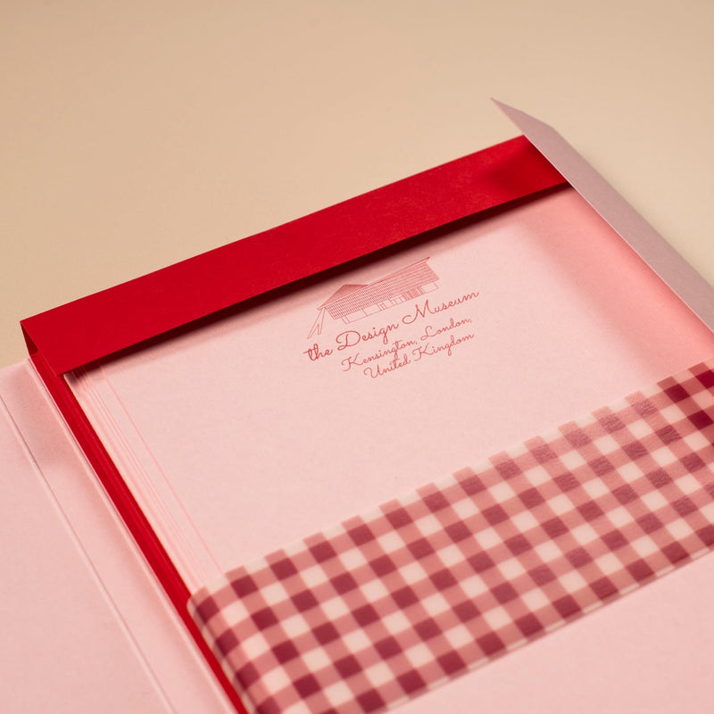 Pink fabric with a checkered pattern inside an open red box on a beige background