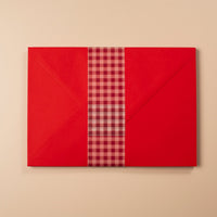 Red gift box with a plaid ribbon on a beige background