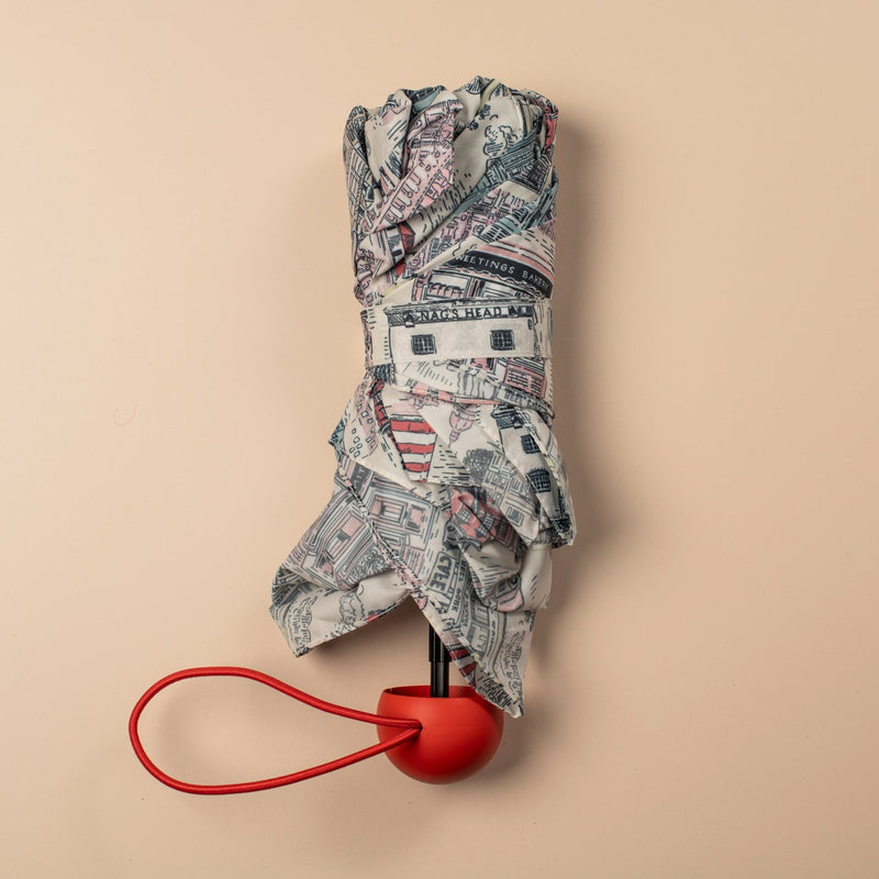Folded umbrella with a red handle on a beige background