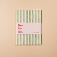 Notebook with striped cover and pink band on a beige background