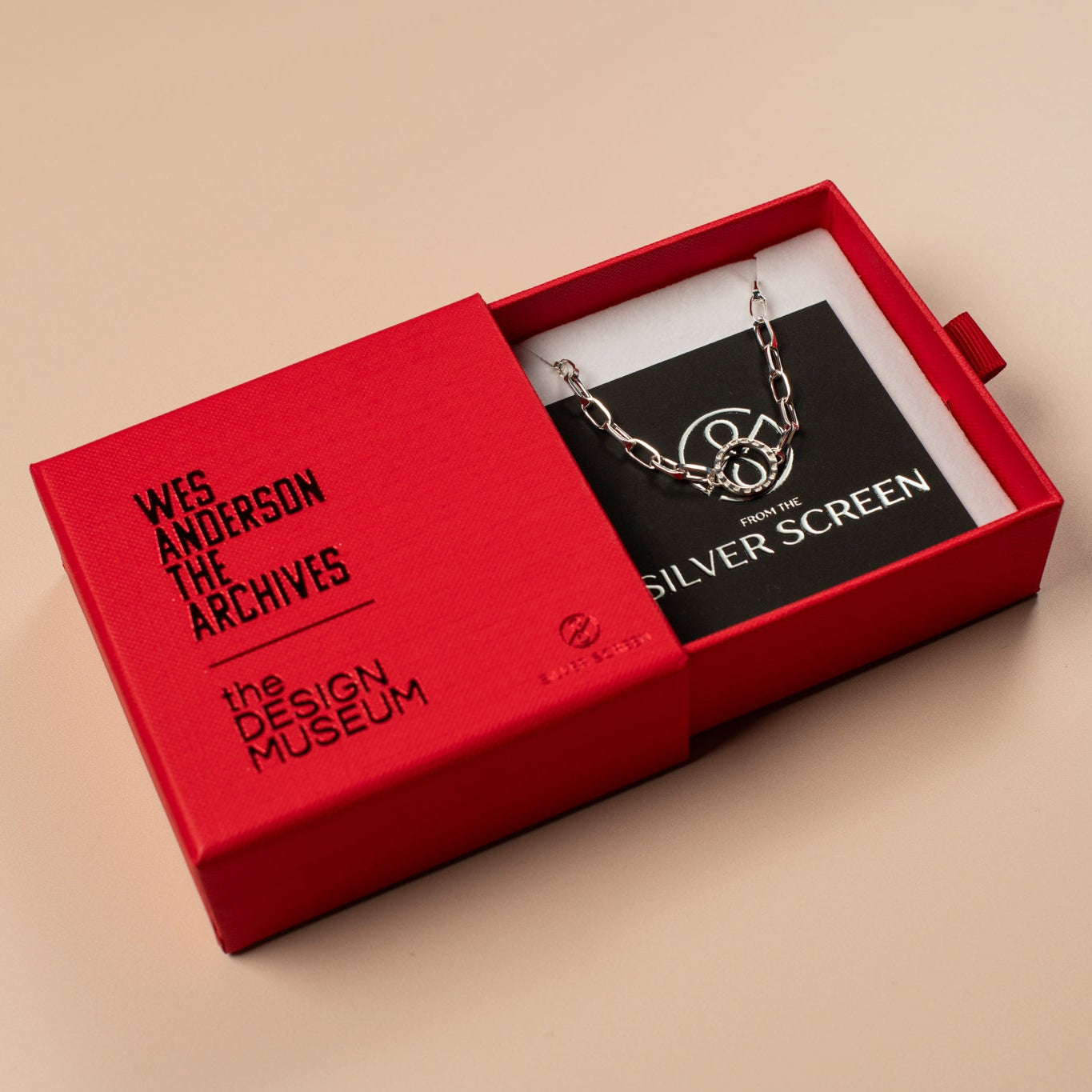 Red box with a necklace inside, featuring 'Wes Anderson The Archives' and 'The Design Museum' branding.