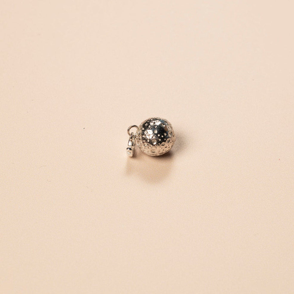 Small silver charm on a beige background
