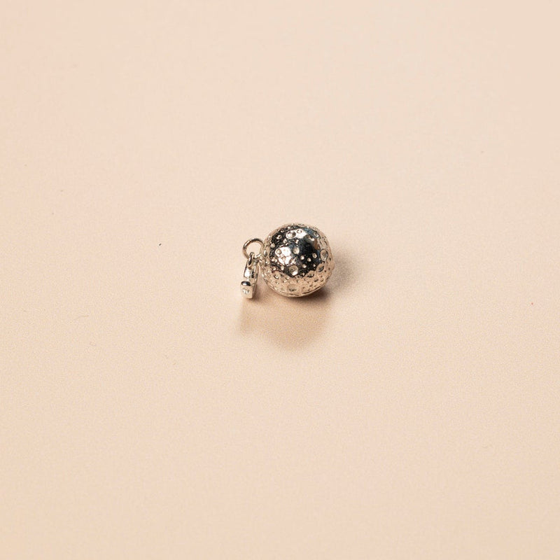 Small silver charm on a beige background