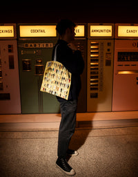 Person standing in front of vintage vending machines with a patterned bag.