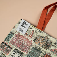 Tote bag with architectural illustrations and a visible brand label on a beige background