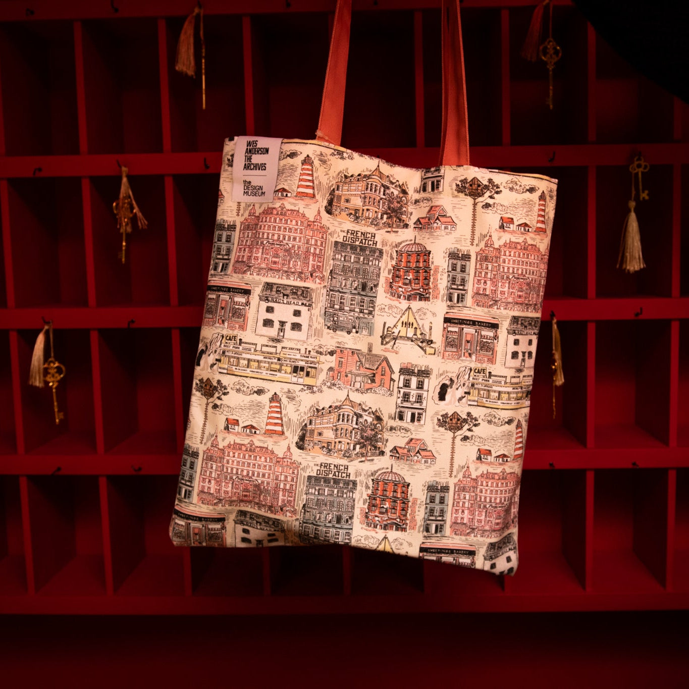 Tote bag with cityscape design hanging on a red rack
