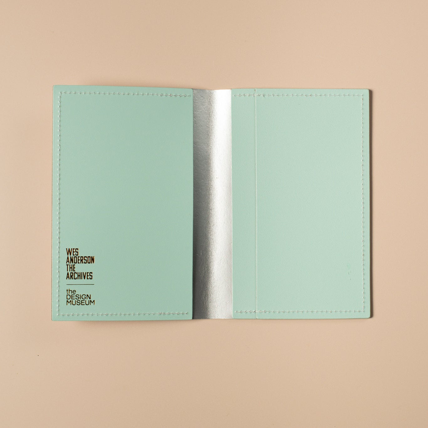 Open light blue passport holder with brand name on a beige background